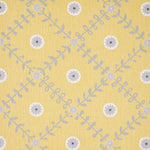 Detail of fabric in a flower and leaf lattice print in gray and white on a yellow field.