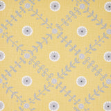 Detail of fabric in a flower and leaf lattice print in gray and white on a yellow field.