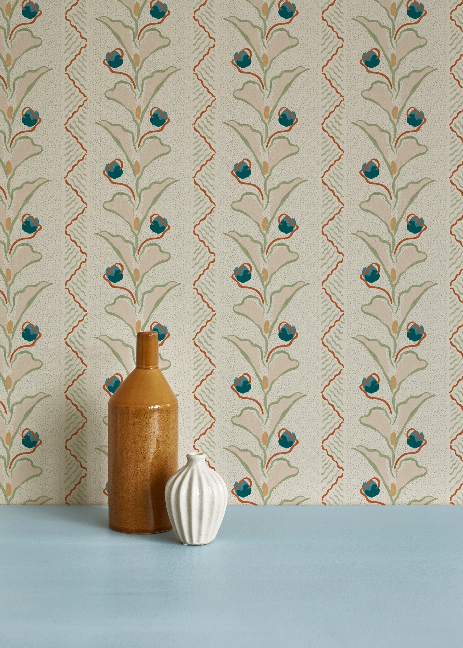 Brown and white ceramic vases against a wallpaper pattern with a playful botanical stripe in cream, pastel pink and accents of red and blue. 