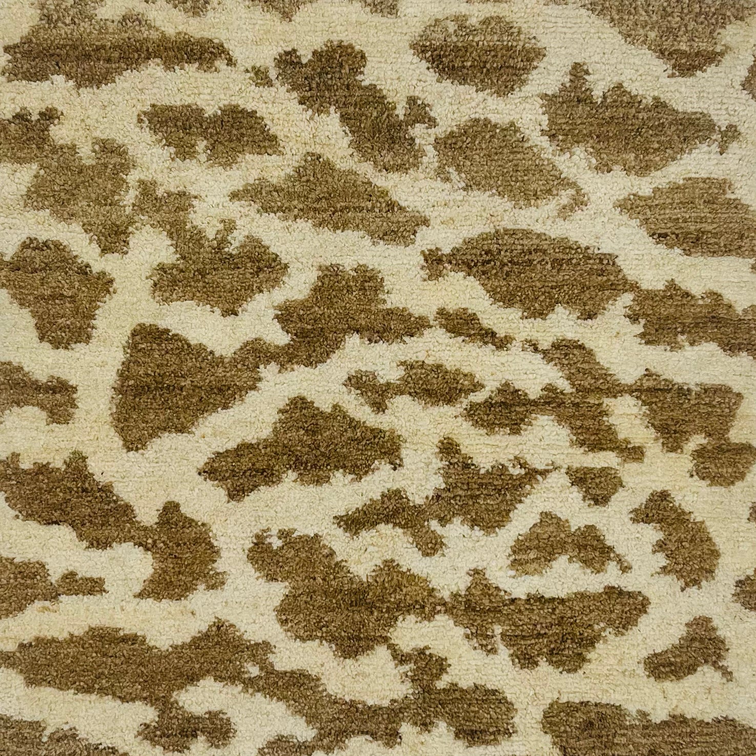 Handknotted rug swatch in natural fibers in giraffe pattern in white and taupe.