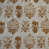 Detail of fabric in a repeating vase and plant print in rust on a mottled cream field.