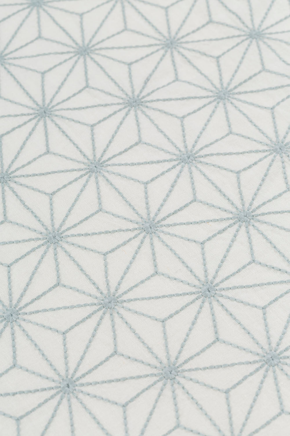 Fabric yardage with an embroidered floral lattice print in light gray on a cream field.