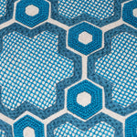 Detail of fabric with a geometric prism pattern embroidered in shades of blue on a white field.