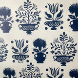 Detail of wallpaper in a repeating vase and plant print in navy on a cream field.