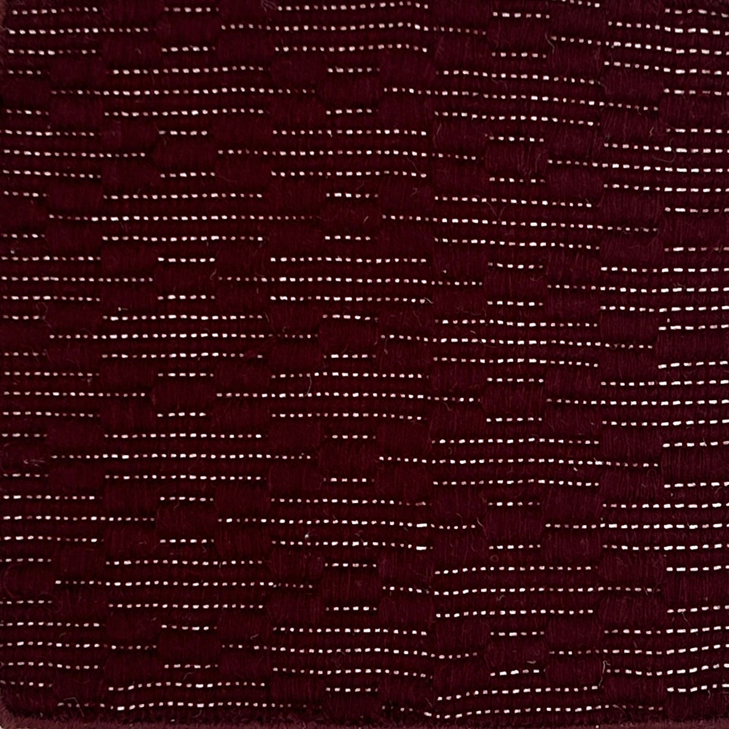 Close-up of a maroon rug with raised lattice pattern
