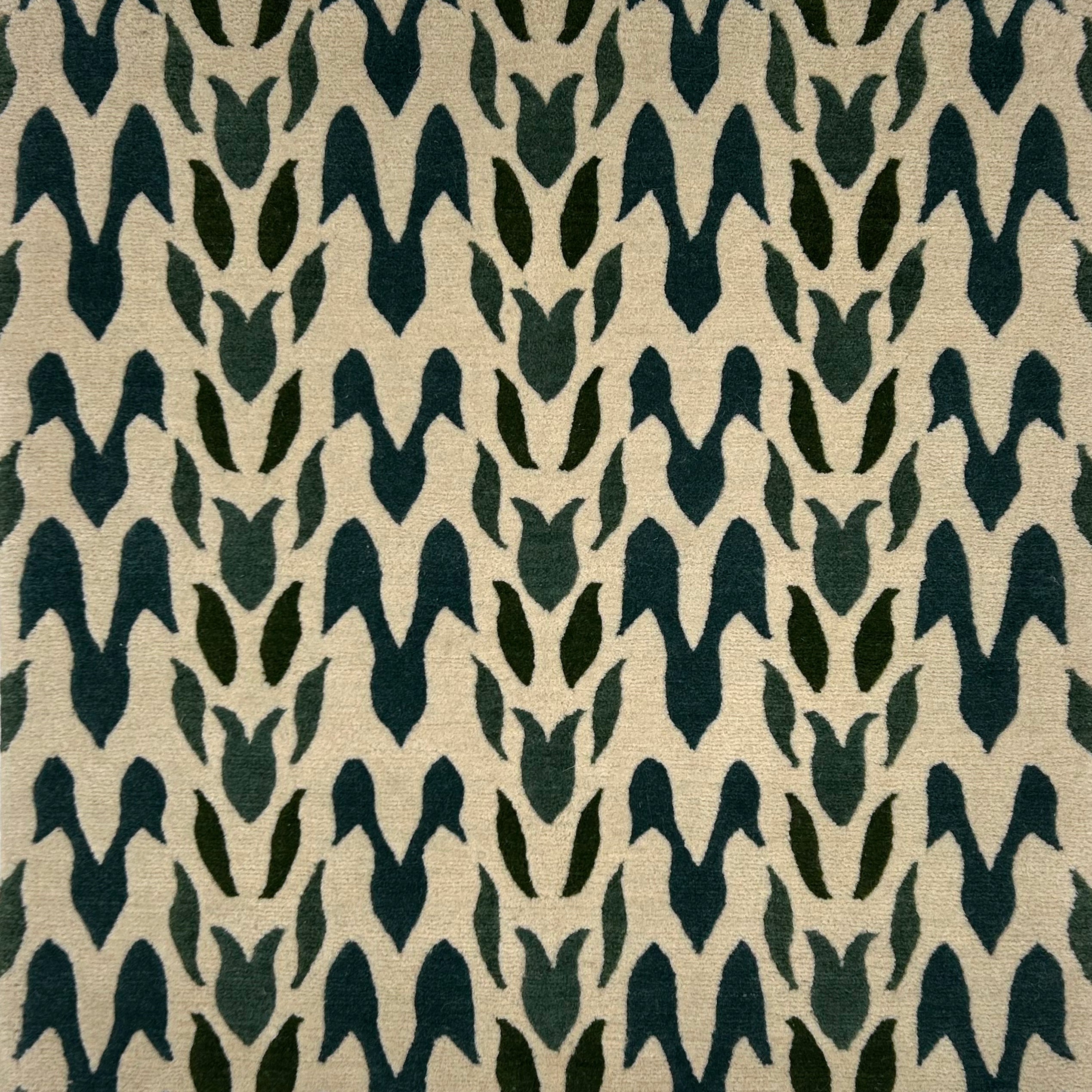 Handknotted rug in a petal pattern in shades of dark green on cream. 