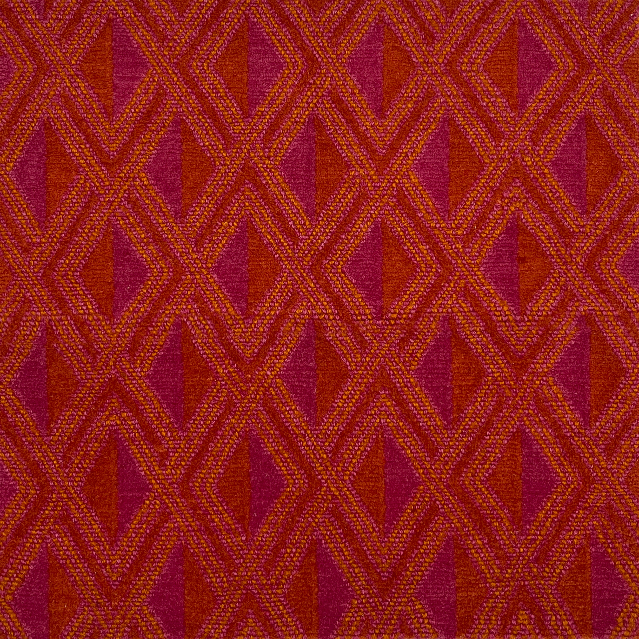 Detail of a woven high-pile rug in an interlocking diamond pattern in pink, red and orange