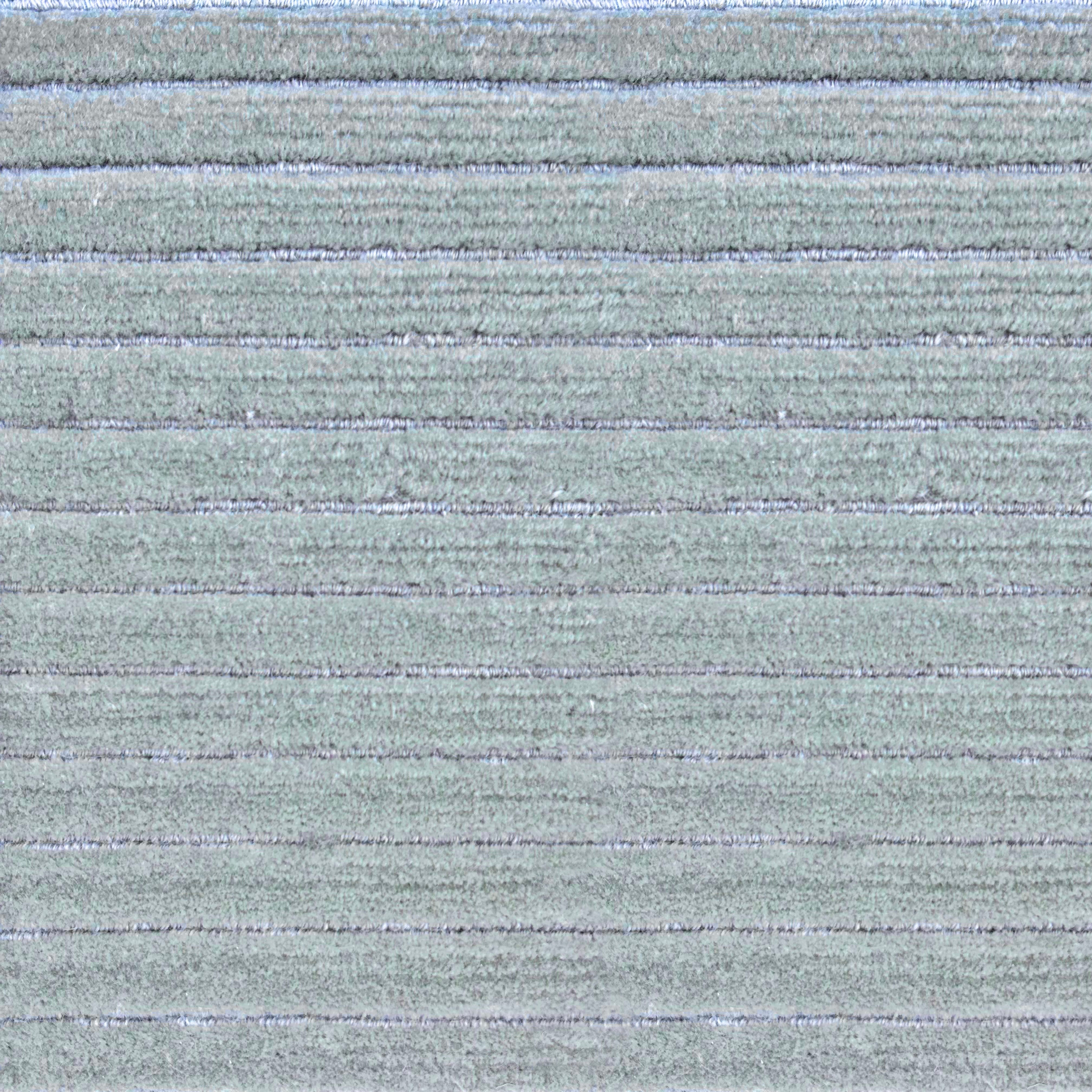 Detail of a handknotted rug in a raised stripe pattern in light grey