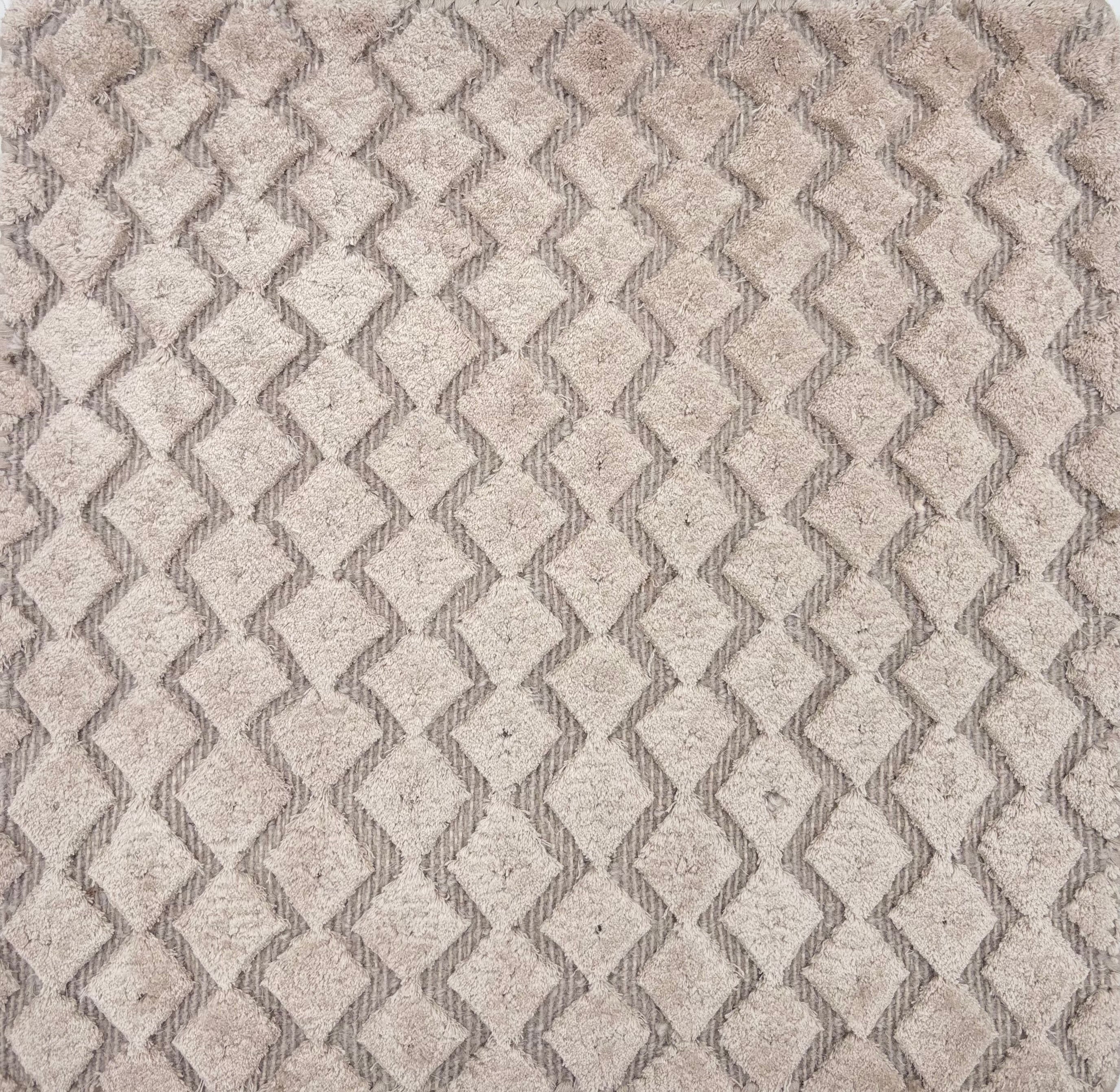 Detail of a hand knotted rug with a raised cut pile diamond stripe in grey.