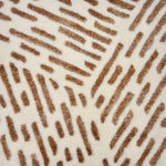 Detail of a handknotted rug in ivory with a brown abstract textural design. 