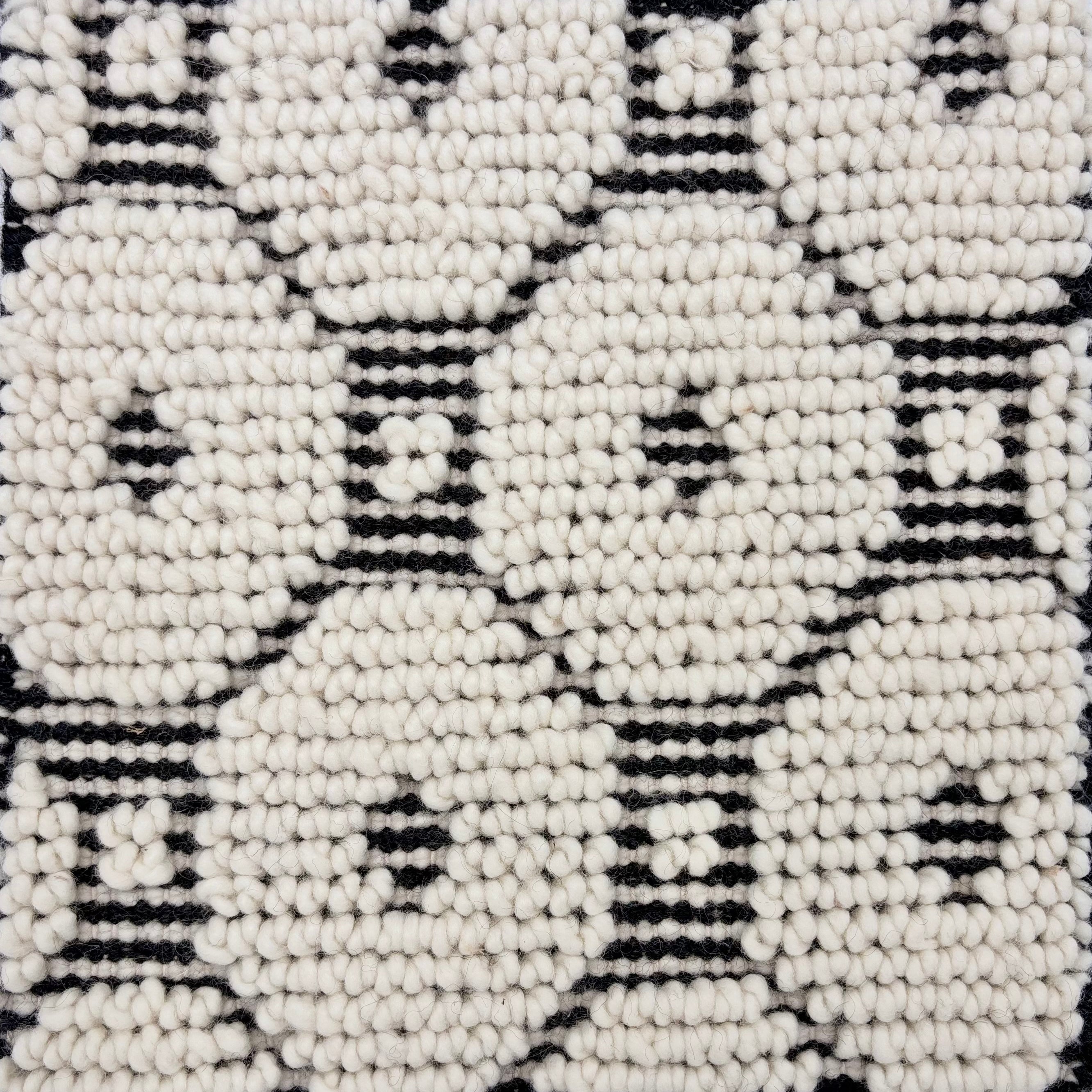 Detail of a handknotted dimensional rug in a geometric pattern in black and white.