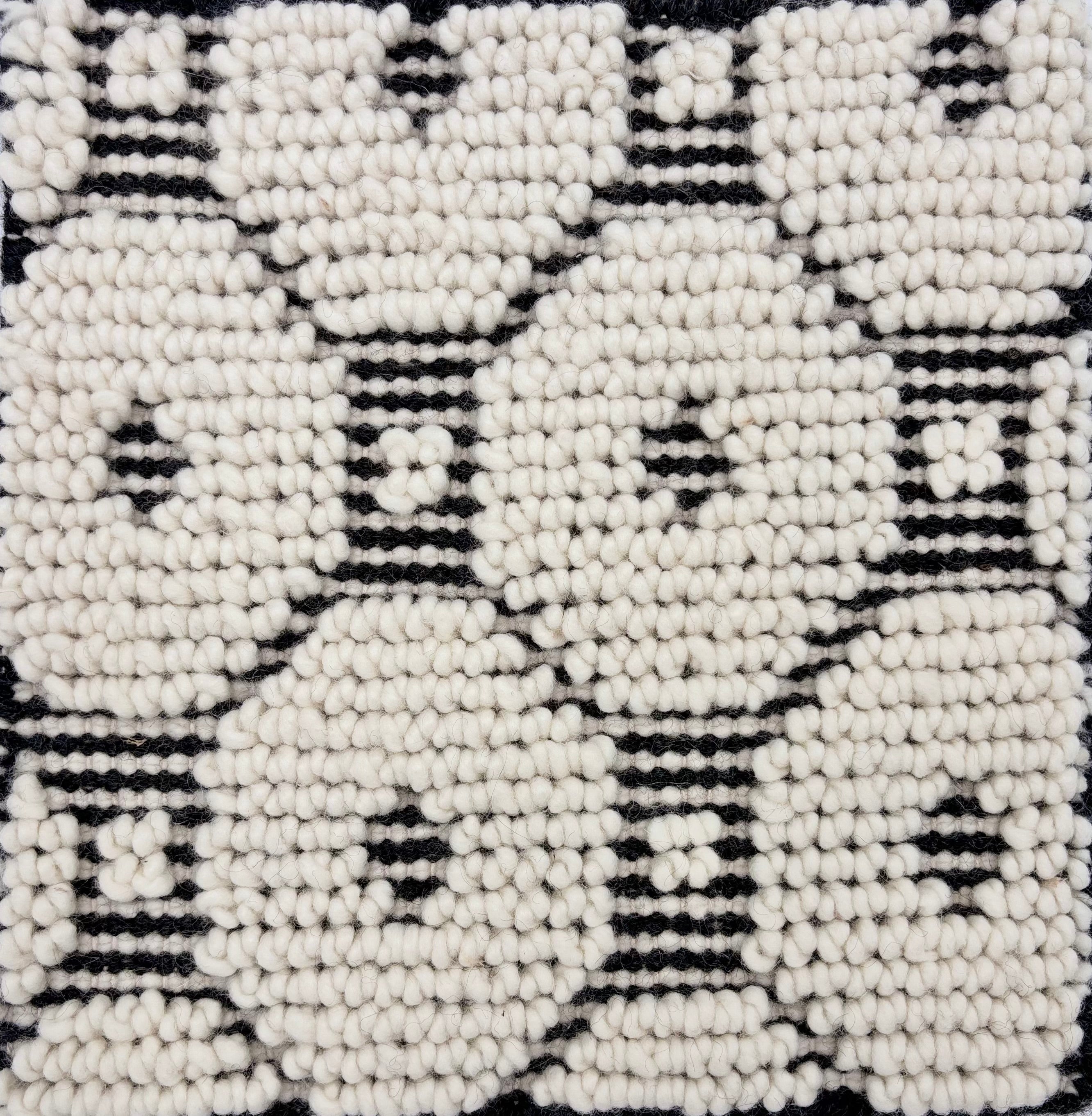 Detail of a handknotted dimensional rug in a geometric pattern in black and white.