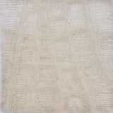 Detail of a handknotted rug in cream in an abstract pattern. 