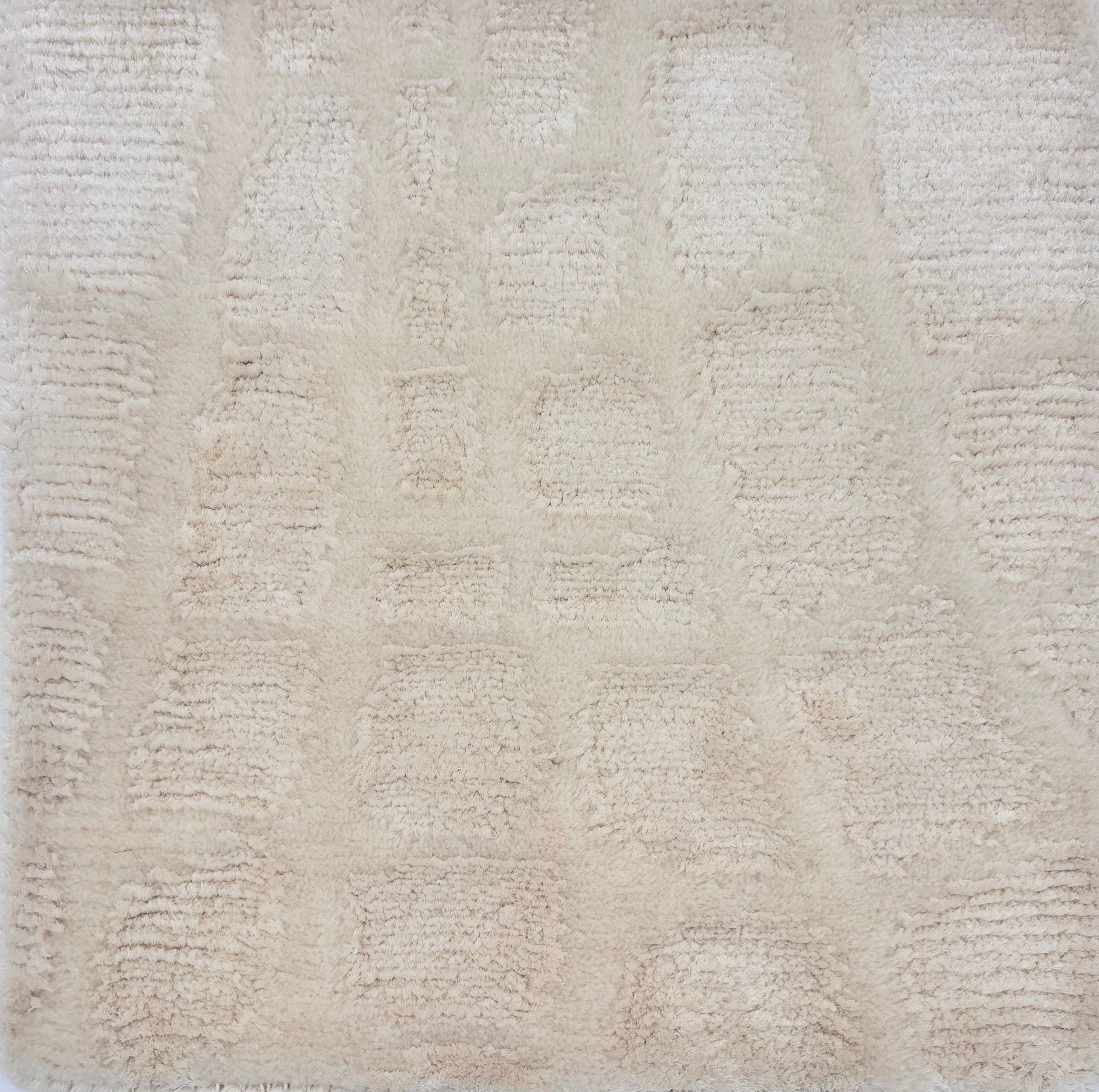 Detail of a handknotted rug in cream in an abstract pattern. 