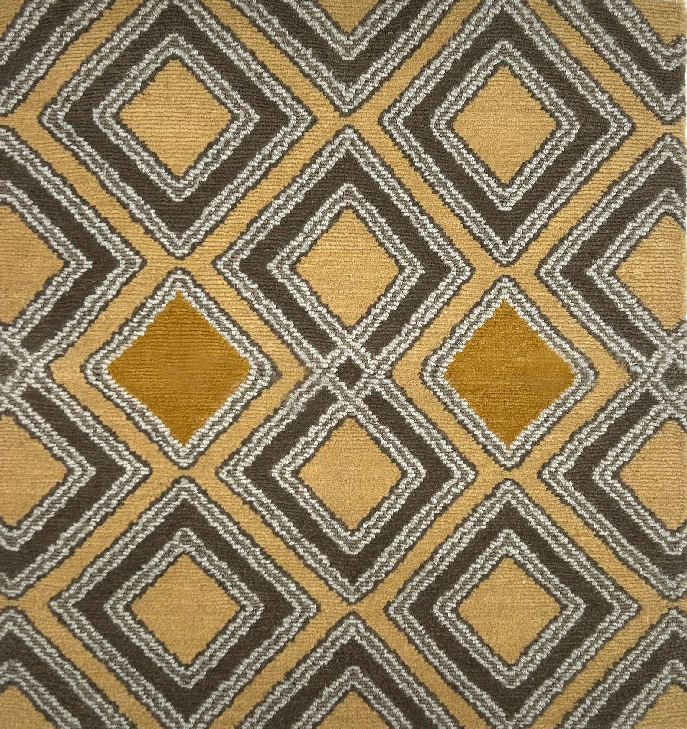 Handknotted rug in a diamond pattern in grey, cream and yellow on a tan field. 
