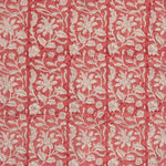 Detail of fabric in a floral block print in cream on a red field.