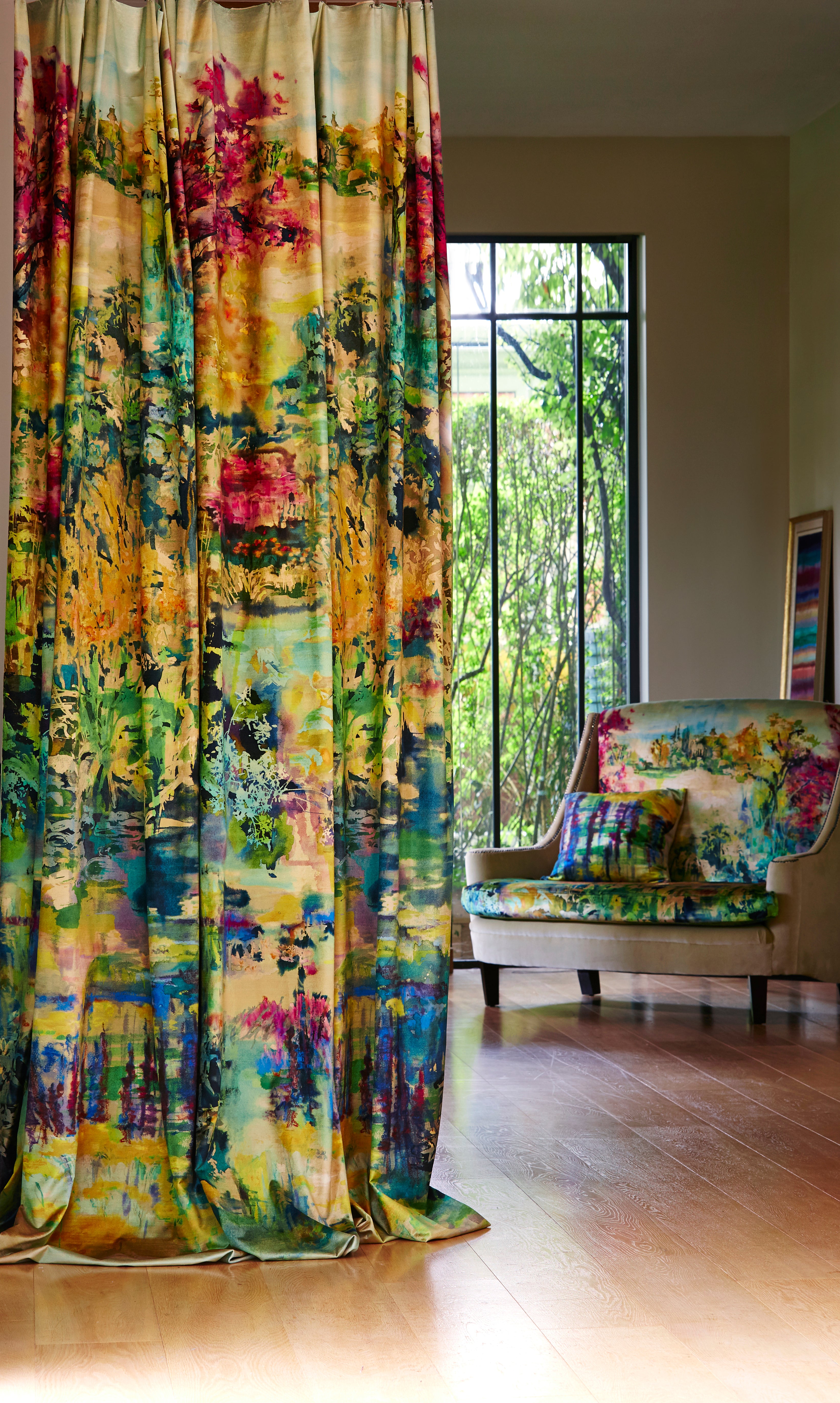 A living space with long curtains and an armchair, both in the same painterly multicolor botanical print.