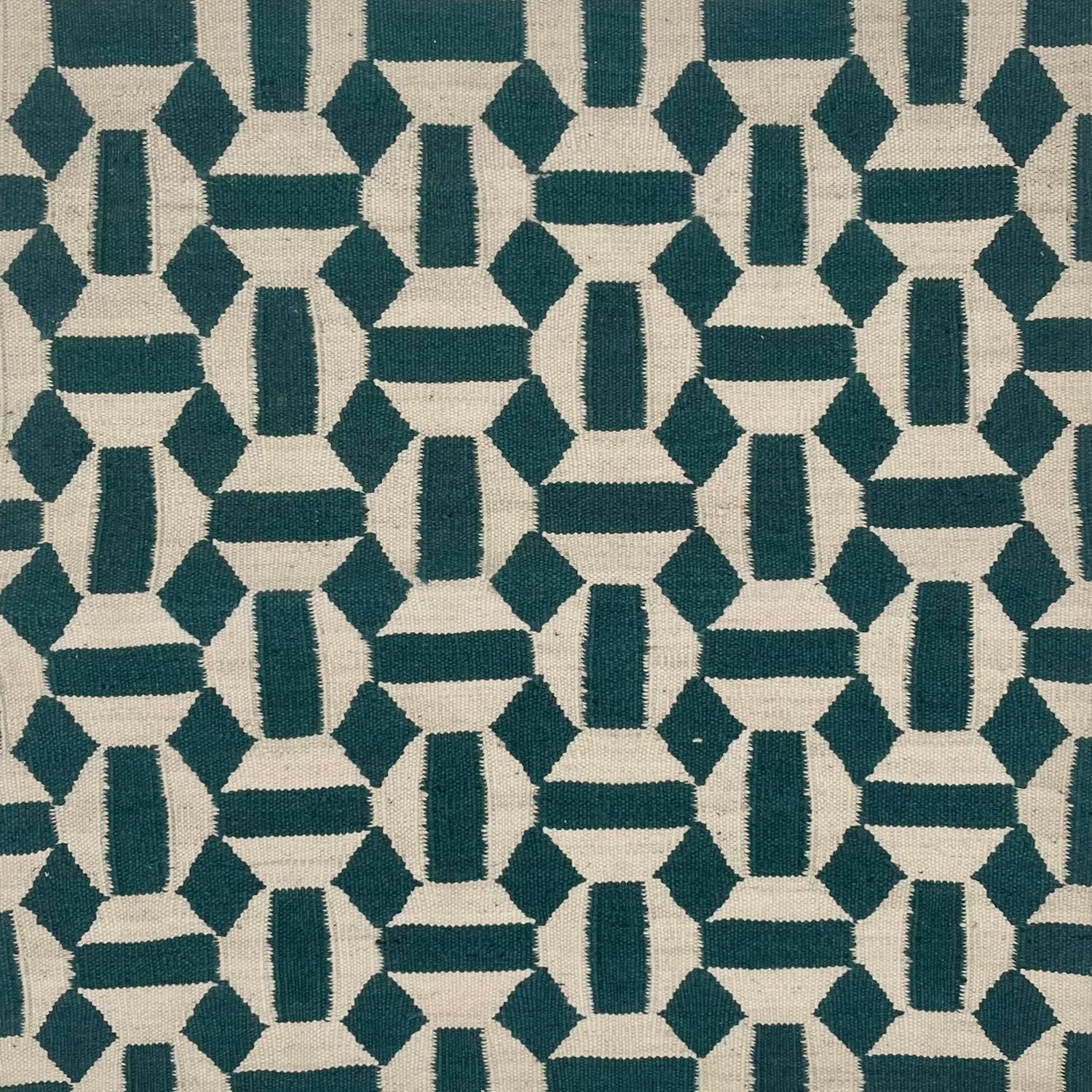 An ivory and deep turquoise rug with a repeating mosaic geometric pattern.