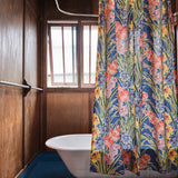 A clawfoot tub with a large-scale floral shower curtain stands in a rustic wooden bathroom.