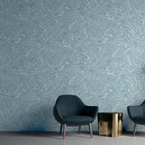 Two navy lounge chairs in front of a wall papered in a painterly botanical print in white and blue on a light blue field.