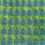 Detail of fabric woven in a repeating leaf print in shades of blue and green.