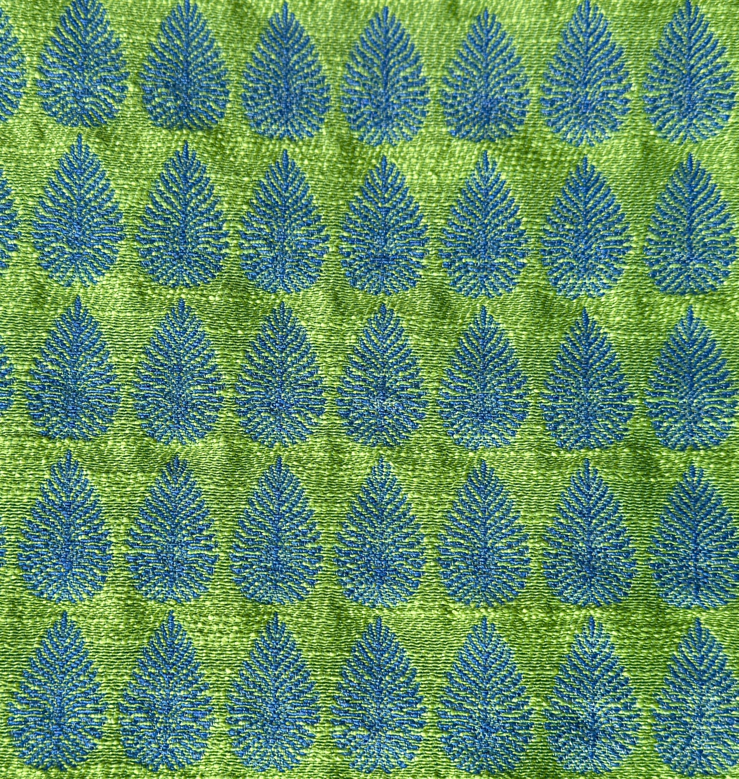 Detail of fabric woven in a repeating leaf print in shades of blue and green.