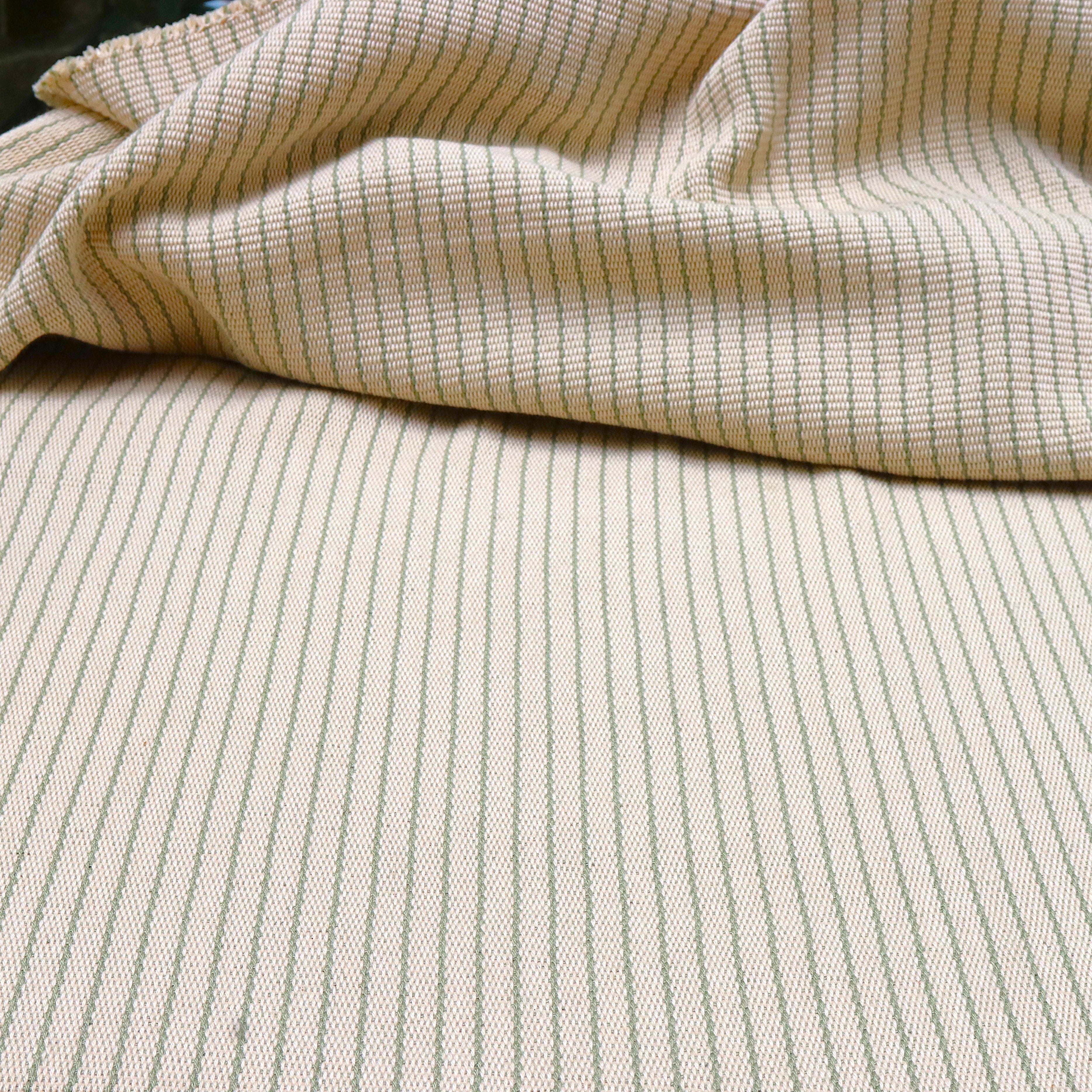 Handwoven fabric gently draped in a cream and sage green stripe.