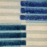 A flatweave rug with pale grey/green and ivory and light blue stripes with raised areas of blue shorter stripes.