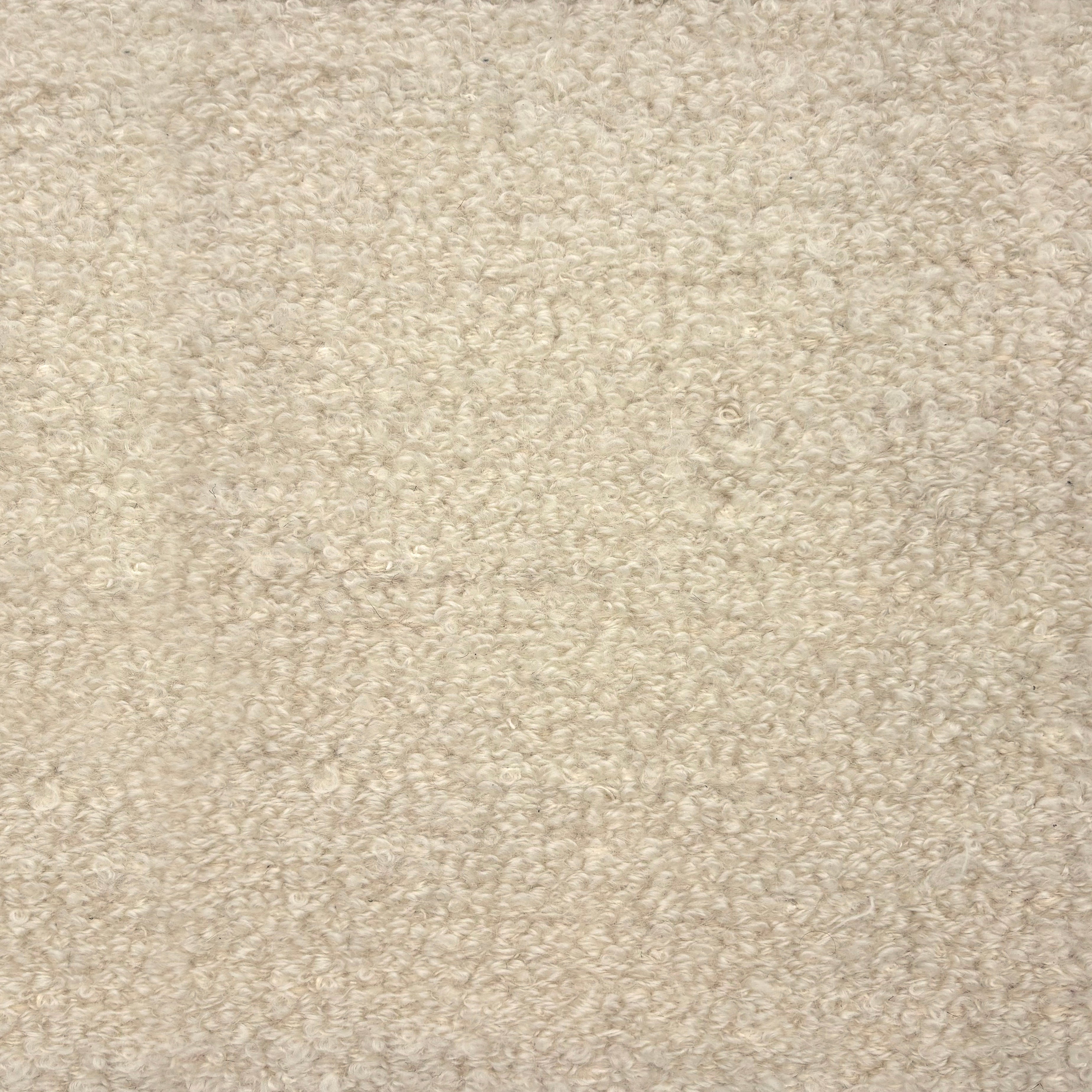 Flatwoven rug in a dense bouclé texture in cream.