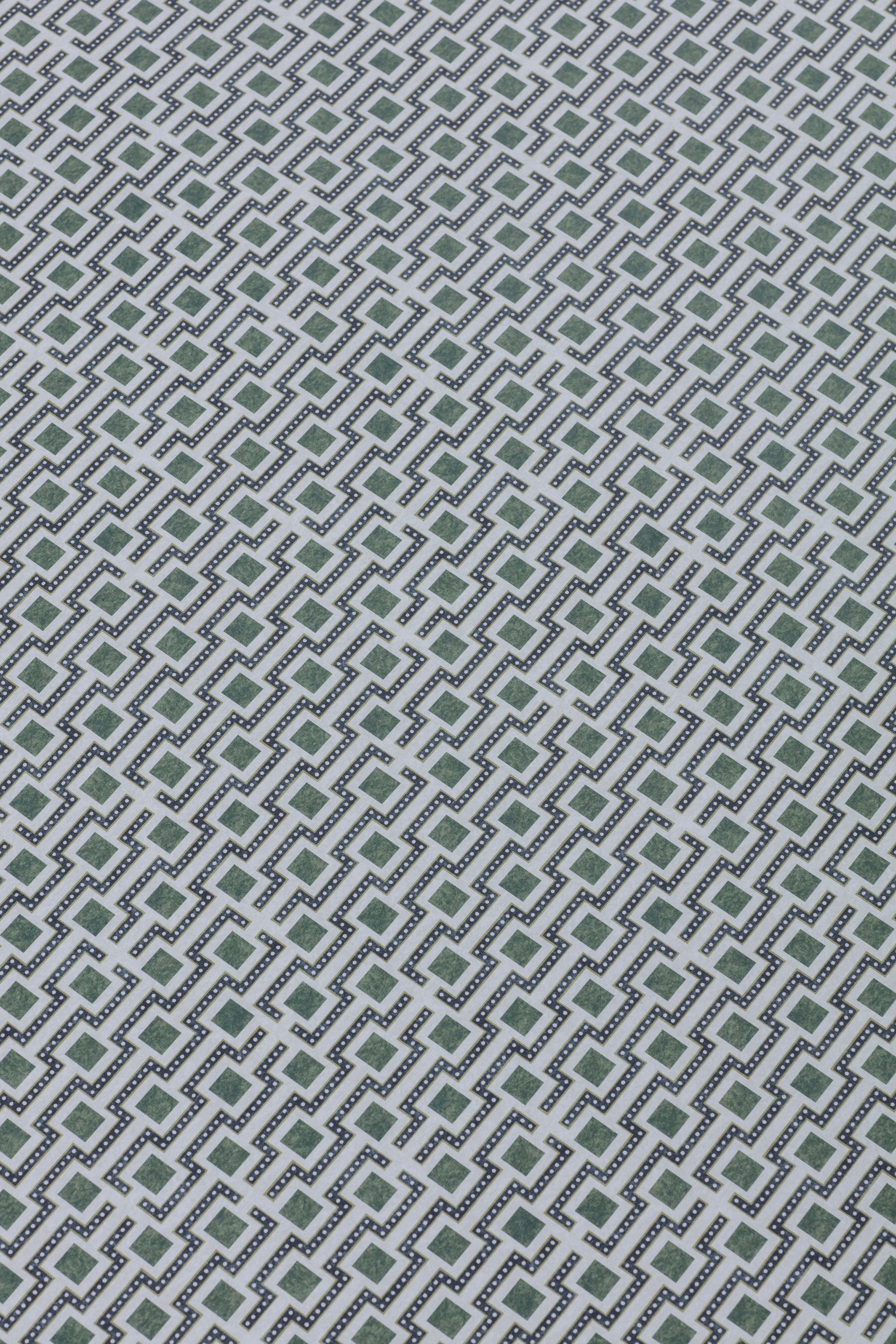 Detail of a wallpaper panel in a geometric grid print in shades of green, blue and gray.