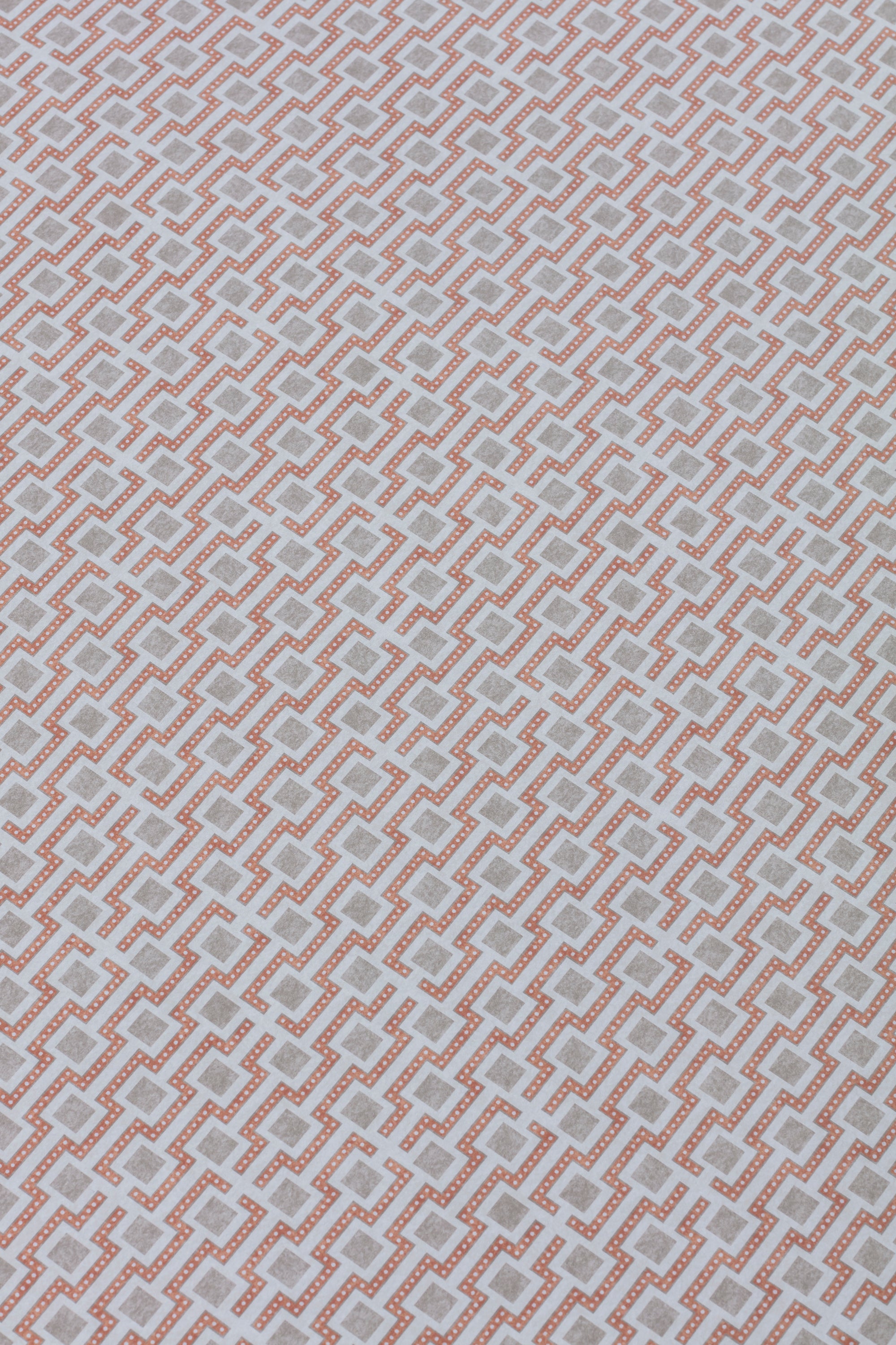 Detail of a wallpaper panel in a geometric grid print in shades of pink and gray.