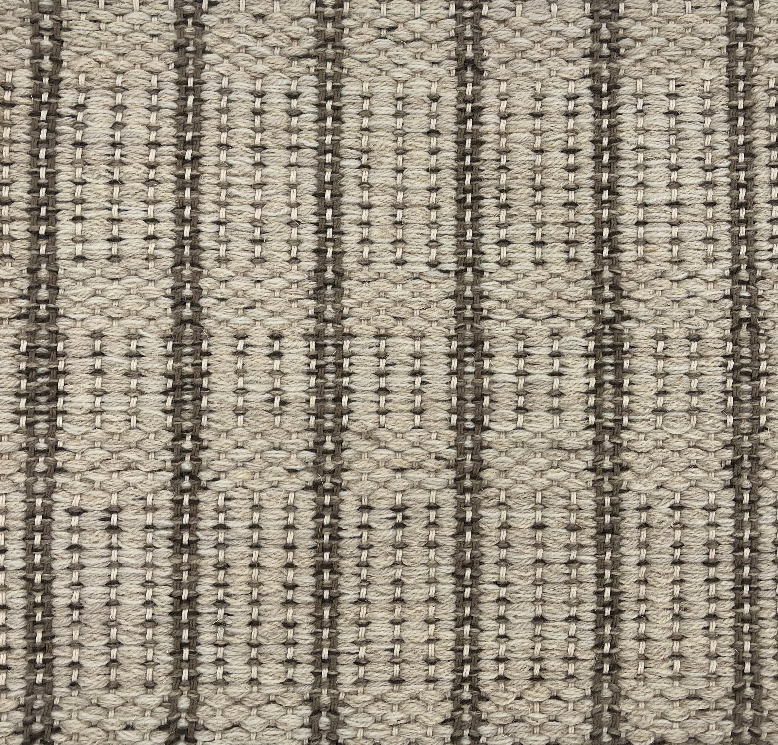 Handwoven rug detail in a stripe design in cream and brown