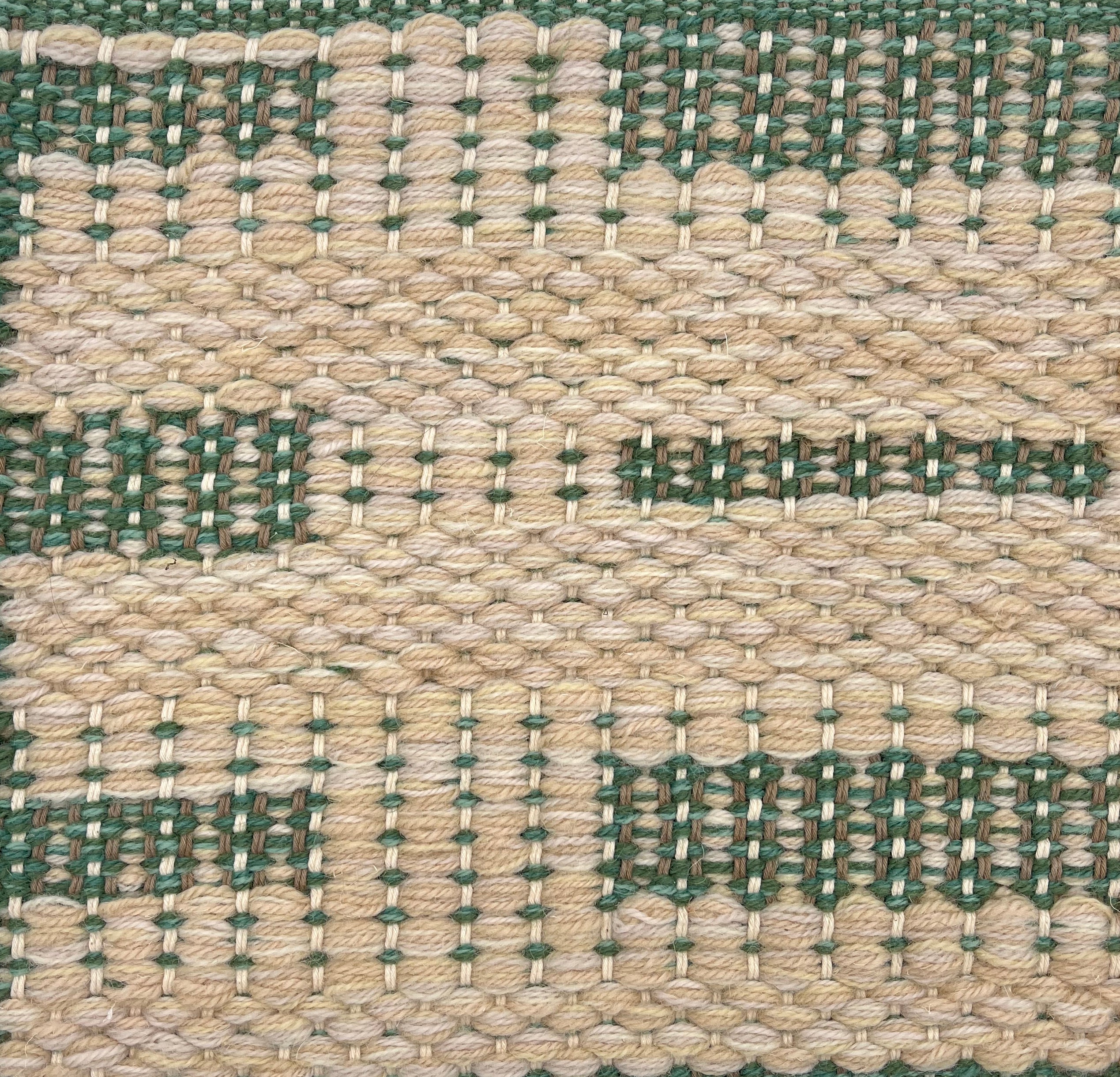 Handwoven rug detail in a contemporary design in green and cream