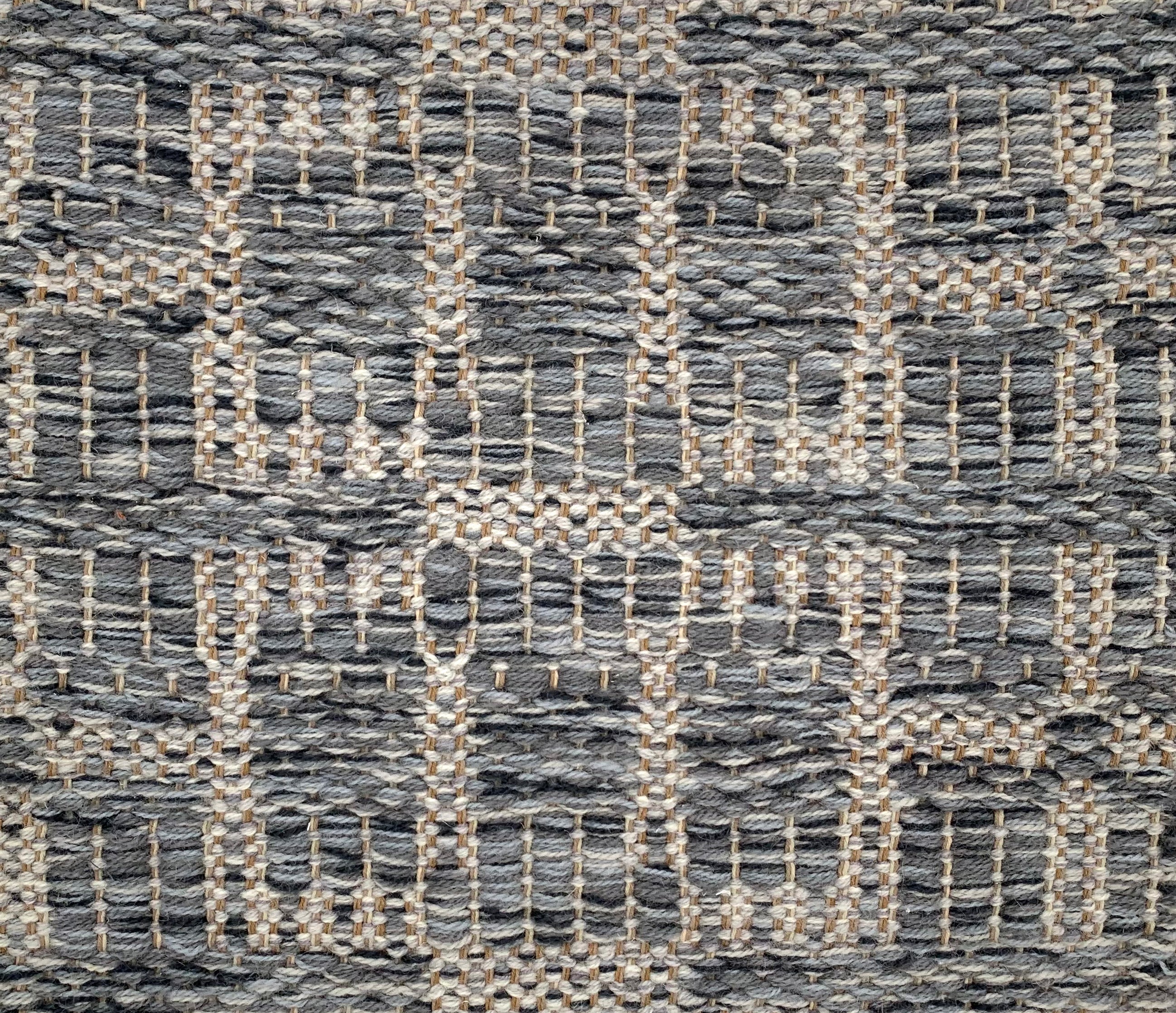 Handwoven rug detail in a geometric design in grey and beige