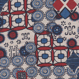 Detail of fabric in a dense curvilinear print in shades of blue, red and black on a tan field.