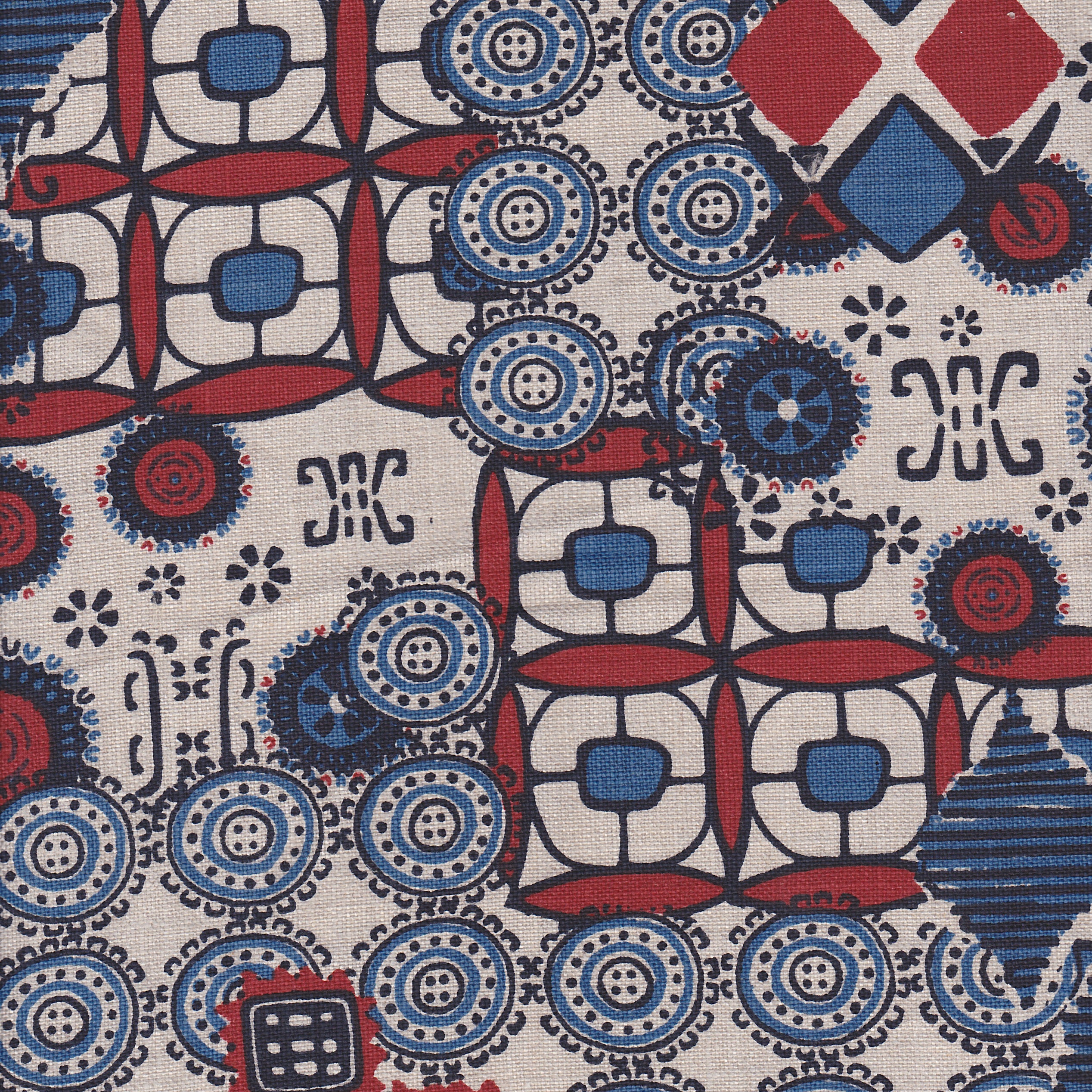 Detail of fabric in a dense curvilinear print in shades of blue, red and black on a tan field.