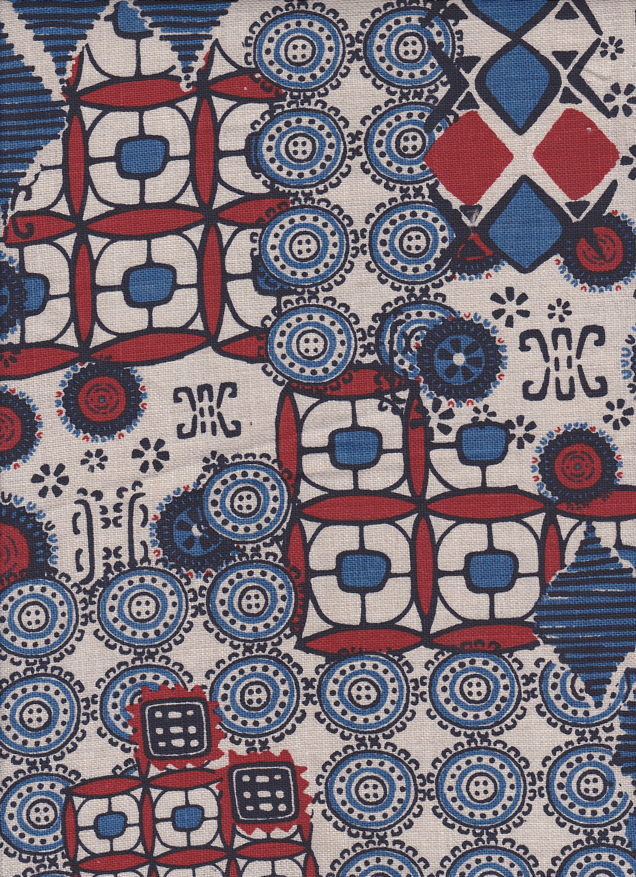 Detail of fabric in a dense curvilinear print in shades of blue, red and black on a tan field.