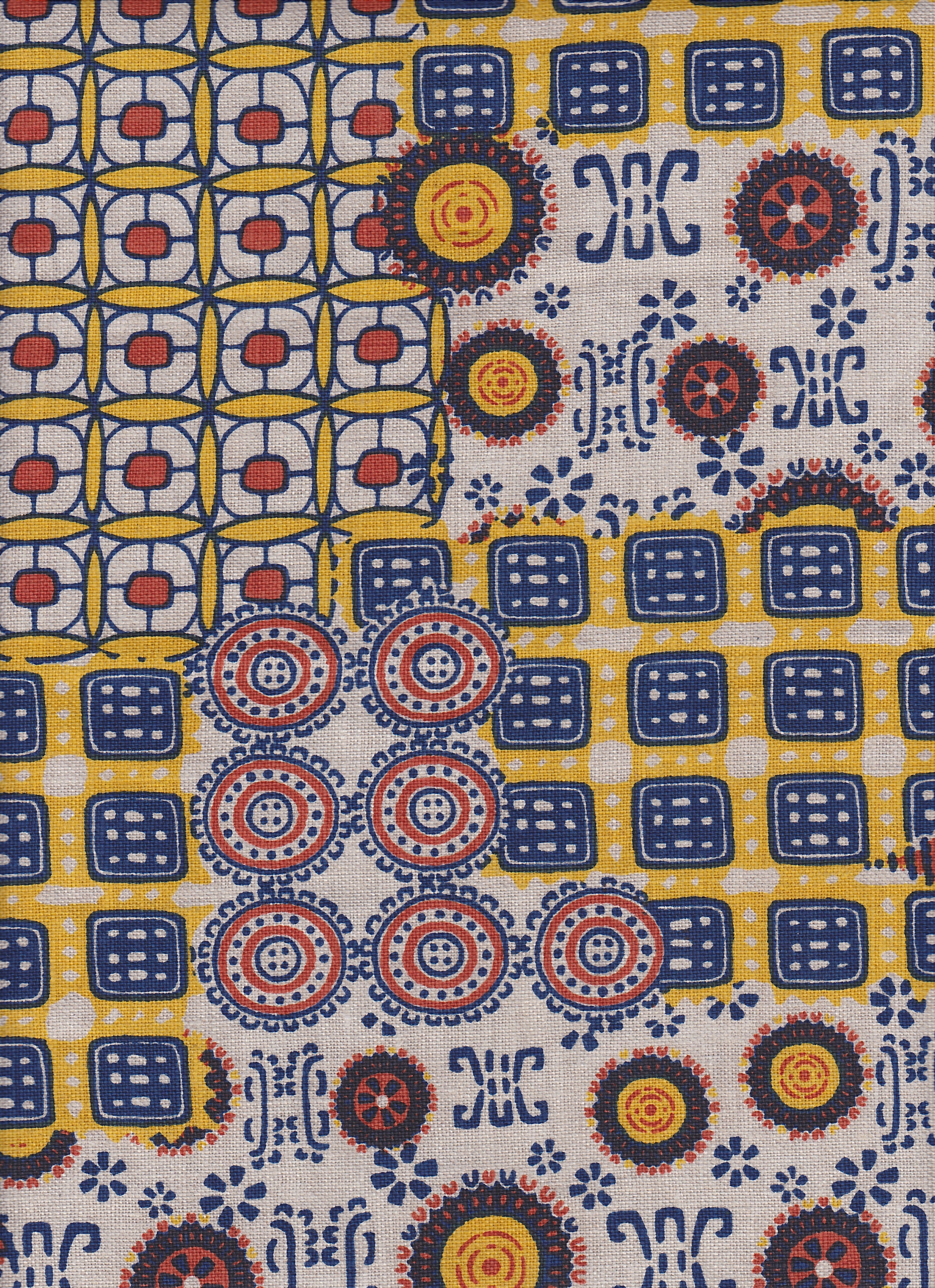 Detail of fabric in a dense curvilinear print in shades of blue, red and yellow on a tan field.