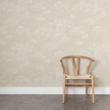 A wooden chair stands in front of a wall papered in a painterly cloud pattern in white on a cream field.