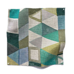 Square fabric swatch in a playful repeating geometric print in shades of blue, green, white and brown.