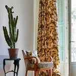 A living space with long curtains and an armchair, both in the same abstract brown and cream paint print.