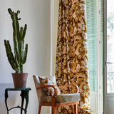 A living space with long curtains and an armchair, both in the same abstract brown and cream paint print.