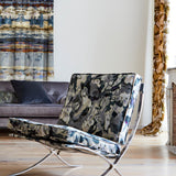 A modernist armchair upholstered in an abstract paint print in shades of blue, gray and cream.