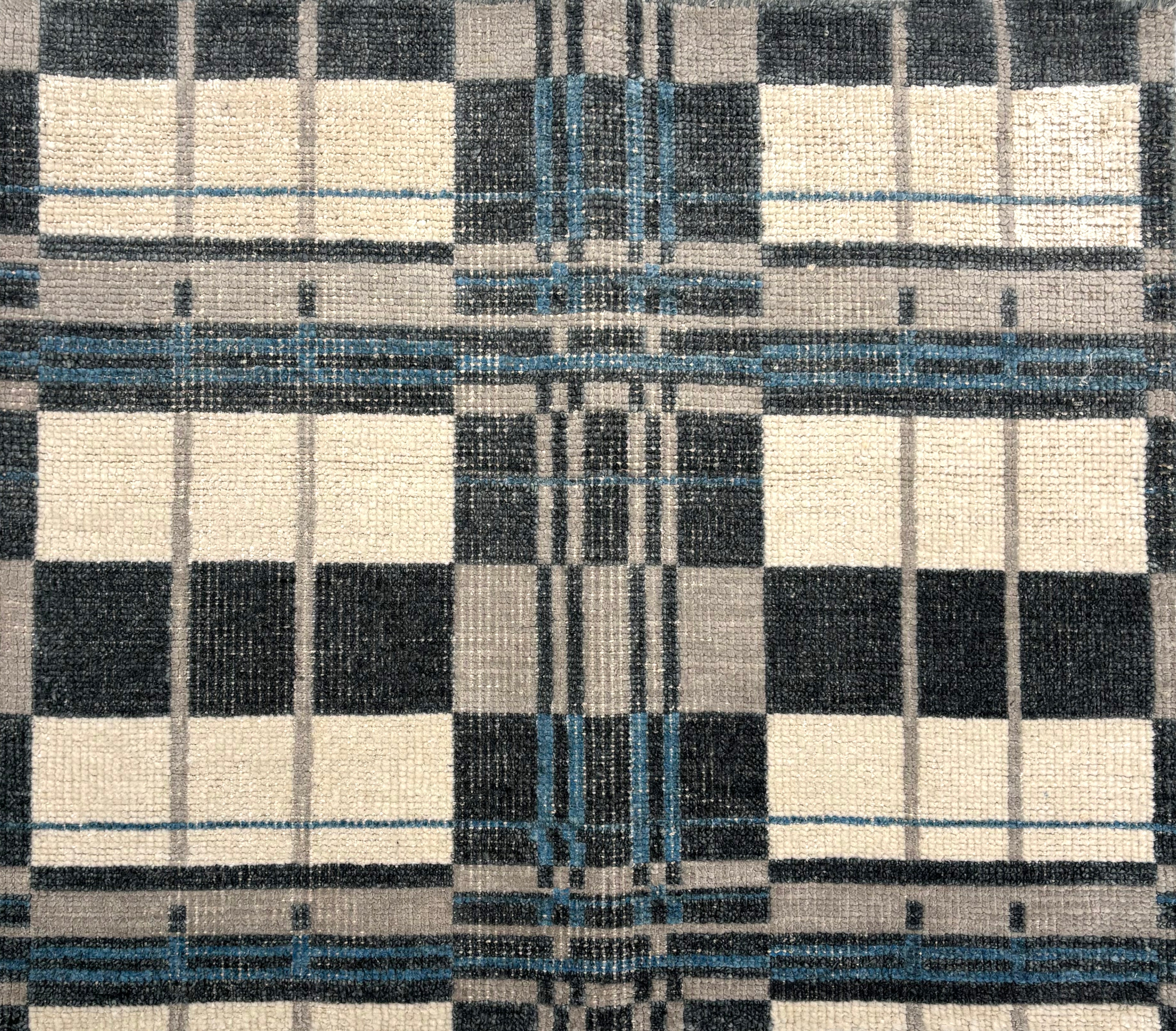 Handwoven rug in a bold windowpane plaid pattern in black, white, grey and blue. 