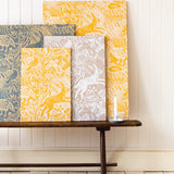 A wooden bench topped with several wallpaper swatches of a playful rabbit and bird print in a variety of colorways.