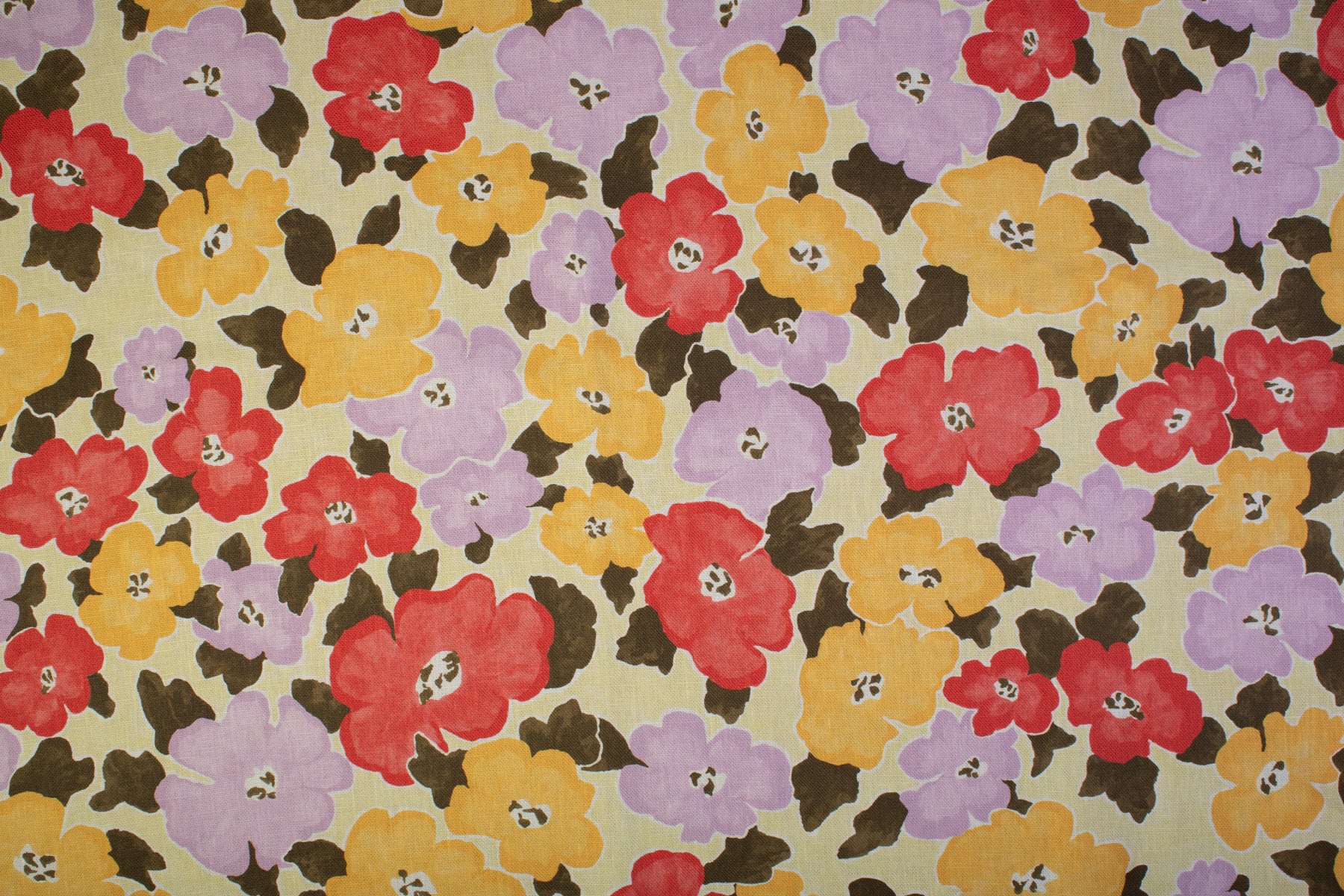 Detail of fabric in a painterly floral print in shades of pink, red and purple.