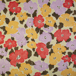 Detail of fabric in a painterly floral print in shades of pink, red and purple.