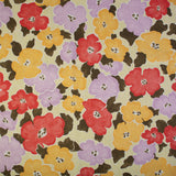 Detail of fabric in a painterly floral print in shades of pink, red and purple.