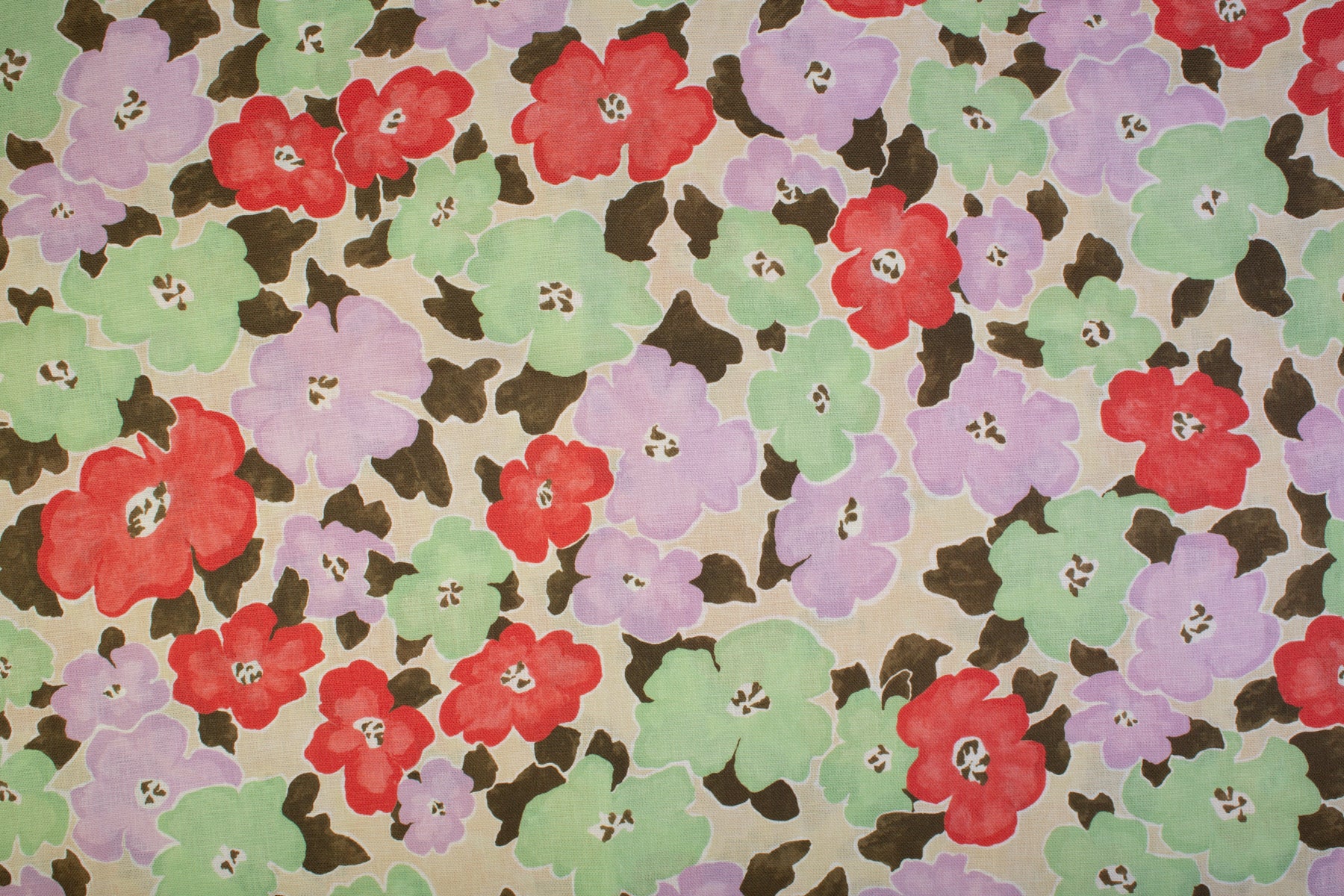 Detail of fabric in a painterly floral print in shades of pink, red, green and tan.