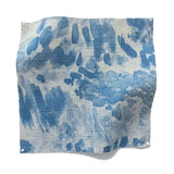 Square fabric swatch in a painterly cloud print in shades of blue and navy on a cream field.